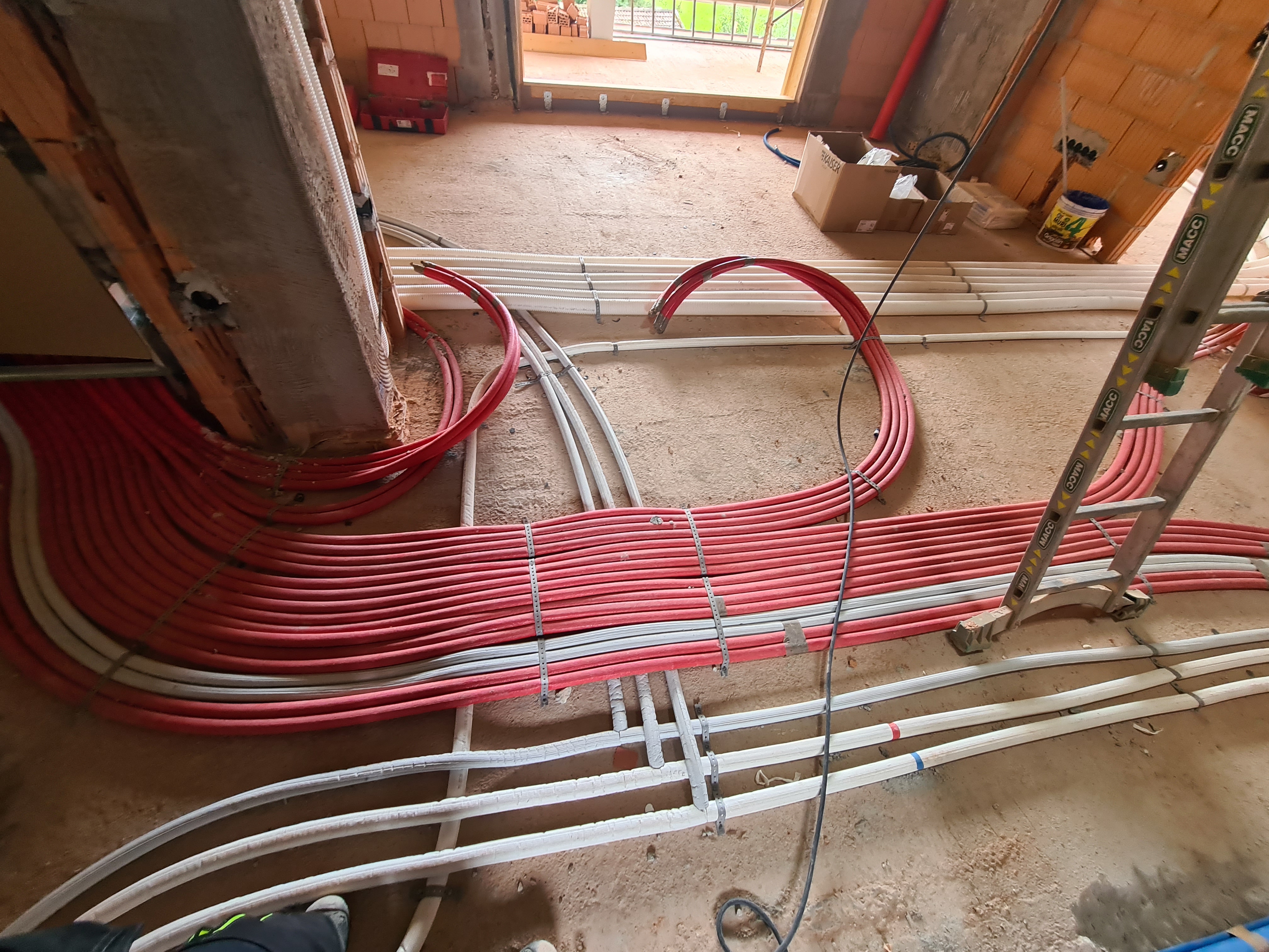 Gebündelte rote und weiße Installationsleitungen auf dem Rohboden